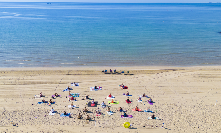 persone che praticano yoga in spiaggia all’alba riprese da un drone